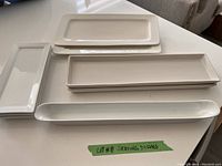 Six white ceramic serving dishes laid out on a surface, showing their shapes and sizes.