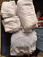 Folded assortment of white towels in terry cloth and waffle weave textures shown stacked on a dark surface.