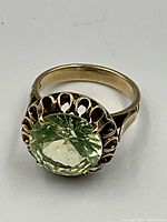 Ring on white background showing front view of green stone and scalloped bezel