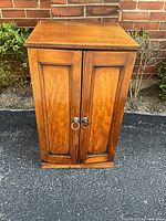 Front view of closed oak specimen cabinet with paneled doors and brass ring pulls