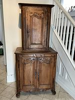 Full front view of two-piece walnut cupboard against wall