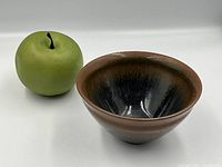 Side view of tea bowl next to green apple for scale