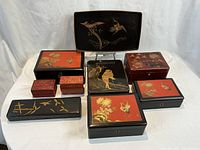 Overview of nine lacquered boxes and one tray arranged on white background