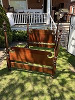 Front view of queen-size mahogany bed frame with headboard and footboard installed, side rails detached.