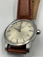 Front view of Omega Seamaster watch showing silver dial, applied markers, dauphine hands and leather strap