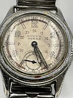 Close-up of watch dial showing Rolex and Birks branding, Arabic numerals, patina