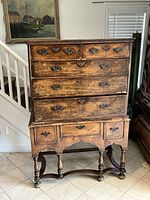 Front view of walnut chest on stand showing six drawers and brass pulls