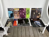Photo showing 9 classic jazz vinyl LPs arranged on white shelving, clearly visible album art including Oscar Peterson and Duke Ellington records.