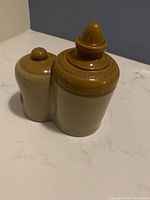 Angle view of the bird water feeder showing the two-tone beige and brown glaze, the capped water container, and the rounded water bowl base.