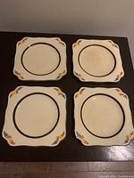 Four square dessert plates arranged in a 2x2 grid showing shape, design, and wear.