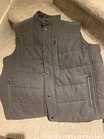 Front view of medium grey vest showing front zipper, snap closures, and zippered pockets.