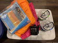Two inflatable mattresses in packaging and two camping lanterns on white tray