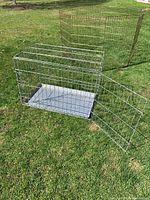 Shows overall dog crate with removable tray and open door placed on grass, displaying crate dimensions and condition.