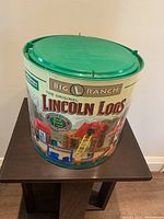 Front side of original round container with Big L Ranch branding and Lincoln Logs logo.