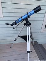 Side view of the fully assembled Sky-Watcher 70mm refractor telescope mounted on an aluminum tripod with accessory tray on a deck.