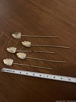 Six antique sterling silver parfait dessert spoons laid out next to a measuring tape showing approximately 6 inches each