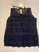 Black lace sleeveless top, front view, showing full lace floral pattern and sleeveless design