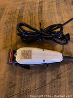 Full view of WAHL Clip Pet clippers placed on a wooden surface with attached power cord coiled.