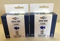 Two new Emzone signal horns in unopened boxes placed side by side on a flat surface