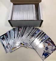 Box filled with a large stack of 2020-21 Upper Deck hockey cards with many visible on top showing player photos and information.