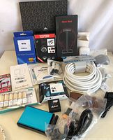 Full overview photo of most electronics items in lot including headphone box, SD cards, cables, battery pack, and other accessories.