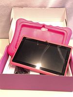Tablet PC with pink protective silicone case inside the box.