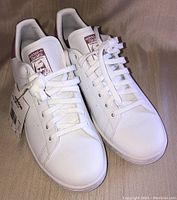 Top down view of pair of white Adidas Stan Smith sneakers with laces tied and shoe tongues visible
