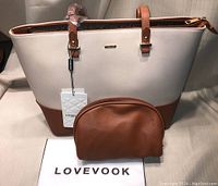 Front view of beige and brown Lovevook purse with matching brown pouch and Lovevook tag.