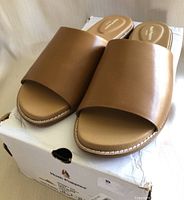 Front angle showing the top and side view of the brown sandals placed on the damaged original box.