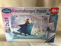 Front view of sealed Ravensburger Disney Frozen puzzle box showing two puzzles with 24 pieces each, recommended for ages 4+.