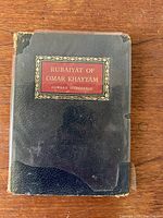 Front cover of antique leather bound book with title plaque on black leather showing wear and corner losses.