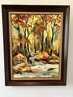 Frontal view of framed oil painting showing signed autumnal forest scene with trees and fall foliage.