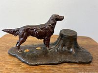 Side view of the figural retriever spaniel dog inkwell mounted on a textured metal base.