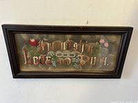 Frontal view of oak framed sampler showing text and floral embroidery