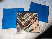 Front cover photo of The Beatles 1967-1970 album with two blue lyric inserts visible in the background.