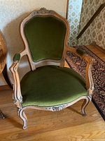 Front view of armchair showing carved crest rail, velvet upholstery and nailhead trim