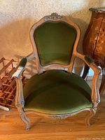 Front view of carved wood frame with green velvet seat and back