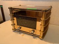 Front and top view of the radio showing the brass frame, glass front with tuning dial and two tuning knobs.