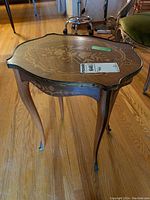 Side view showing the curved legs with brass feet and floral wood inlay on side apron