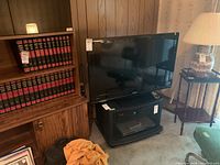 Toshiba 40-inch flat screen TV sitting on black TV stand with glass doors and electric fireplace insert, remote control on the stand.