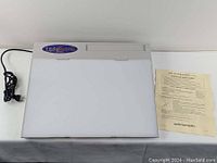 Light Tracer II lightbox powered off with manual beside it, showing device shape and condition.