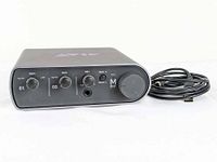 Front view of AVID MBox Mini showing gain controls, large output level dial, headphone jack, and USB cable.