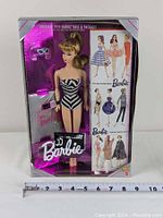Front view of Barbie doll in original unopened box displaying doll wearing black and white striped swimsuit and sunglasses, with bright metallic packaging and 35th Anniversary logo.