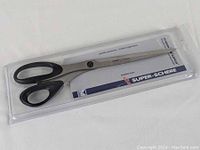 Left handed fabric shears unopened in original clear plastic packaging showing brand and product line labels.