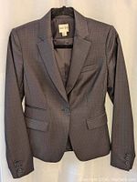 Front view of unbuttoned dark grey plaid Reiss women's blazer size 4 on hanger showing lapels and flap pockets.