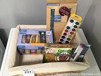Photo of basket containing acrylic paints, crayons, oil pastels, Blick brush set, and tattoos.