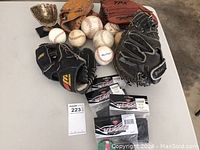View of all gloves, baseballs, and four packages of Vizari Guard Stay protective inserts arranged on a floor surface.