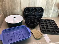Overall lot showing multiple baking pans and silicone molds including muffin tin, bundt pans, and blue silicone mold with butterfly design.