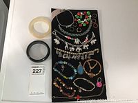 Overview photo showing all bracelets including bangles and charm bracelets laid out on black surface.