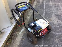 Side view showing steel frame, pneumatic wheels, Honda engine, coiled high-pressure hose, spray wand